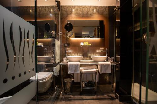 a bathroom with three sinks and two toilets at Hotel Sancho Abarca Petit SPA in Huesca
