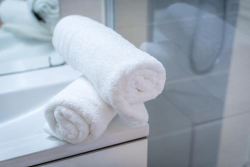 - une pile de serviettes assises sur un miroir dans la salle de bains dans l'établissement Aux Jardins de l'Hôtel de ville - Appartement Hypercentre avec Parking Privé, à Rouen