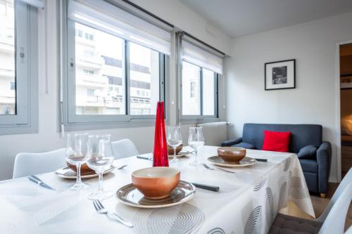 une salle à manger avec une table blanche et des verres à vin dans l'établissement Aux Jardins de l'Hôtel de ville - Appartement Hypercentre avec Parking Privé, à Rouen