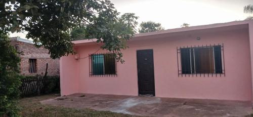 ein rosafarbenes Haus mit schwarzer Tür und Fenstern in der Unterkunft Mburucuya in Mburucuyá