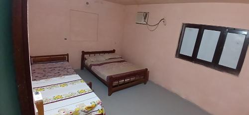 2 Betten in einem kleinen Zimmer mit Fenster in der Unterkunft Mburucuya in Mburucuyá