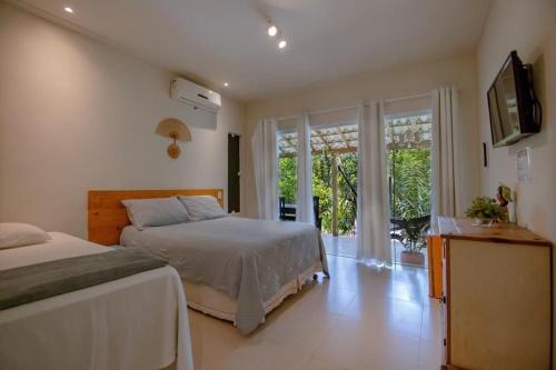 a bedroom with two beds and a large window at Aruana Suites Tranquilidade e Sossego no meio da Natureza a 5km da Vila de Praia do forte in Praia do Forte