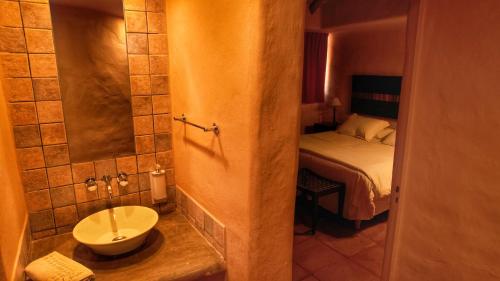 La salle de bains est pourvue d'un lavabo et d'un lit dans la chambre. dans l'établissement Los Colorados Cabañas Boutique, à Purmamarca