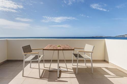 a table and chairs on a balcony with the ocean at Callisto Seaside Homes & Suites in Marathopolis