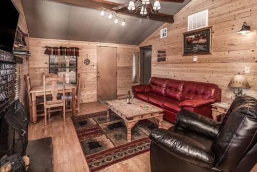 a living room with a leather couch and a table at Canyon Cabins in Ruidoso