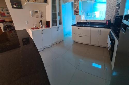uma cozinha com armários brancos e piso em azulejo em Palmas home rental em Palmas