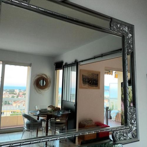un miroir dans une pièce avec une table et une salle à manger dans l'établissement Claloc portes d'azur, à Bandol