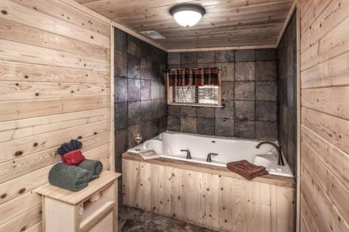Canyon Cabins في رويدوسو: حمام مع حوض استحمام وجدار خشبي