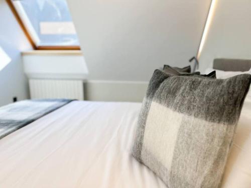 a bed with a gray and white pillow on it at Ático Dúplex De Lujo - CLASIFICACIÓN 5 ESTRELLAS - 8PAX - A Pie Del Centro - 2 PARKINGS l by BonesVacances in Andorra la Vella
