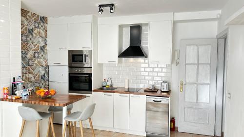 a kitchen with white cabinets and a wooden table at Boutique Apartment Adeje I in Adeje