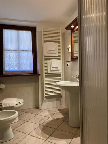 bagno con servizi igienici, lavandino e finestra di Baita Reale ad Alagna Valsesia