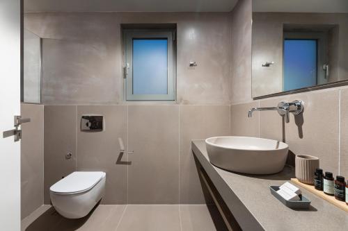 a bathroom with a tub and a sink and a toilet at Callisto Seaside Homes & Suites in Marathopolis