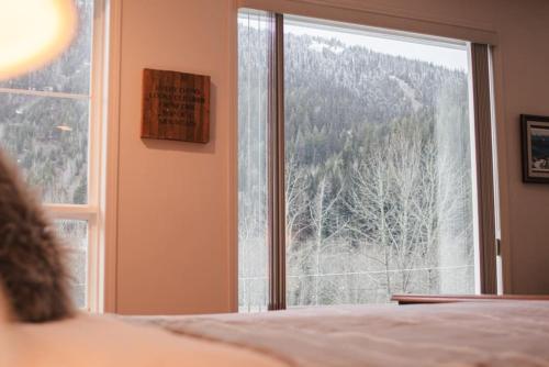 a bedroom with a window with a mountain view at Burfield Lodge, Ski In Ski Out with Hot Tub in Sun Peaks