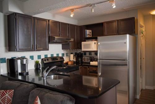 a kitchen with wooden cabinets and a stainless steel refrigerator at Moguls, Lofted Ski in Ski Out with Hot Tub Access in Panorama