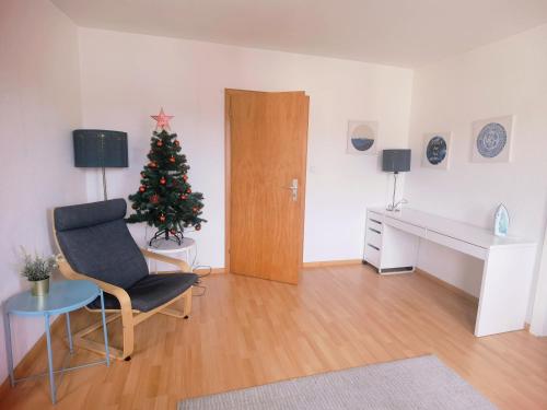 ein Wohnzimmer mit einem Weihnachtsbaum und einem Stuhl in der Unterkunft Bad Homburg Wohnung für 5 Personen in Bad Homburg vor der Höhe
