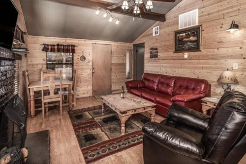 a living room with a leather couch and a table at Canyon Cabins in Ruidoso