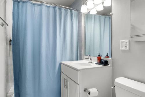 a bathroom with a sink and a blue shower curtain at Penthouse Living near DC and Metro in Arlington