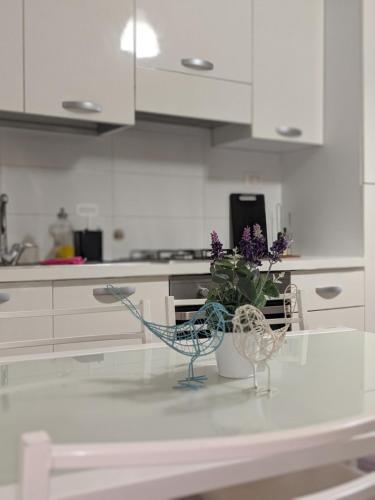 uma cozinha branca com um vaso de flores sobre uma mesa em Verbania Centro Storico 2 camere em Verbania