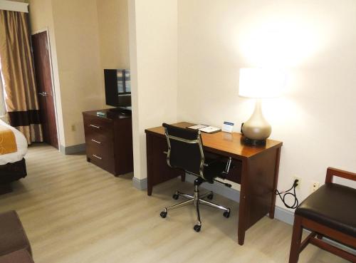 a hotel room with a desk with a lamp and a chair at Comfort Suites in Twinsburg