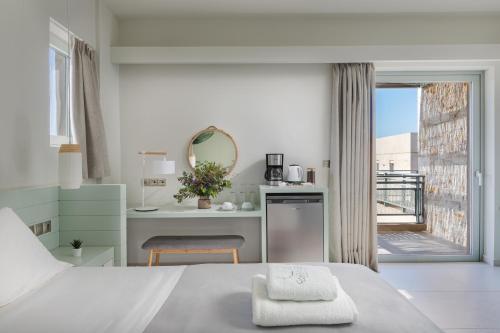 a white bedroom with a bed and a bathroom at Callisto Seaside Homes & Suites in Marathopolis