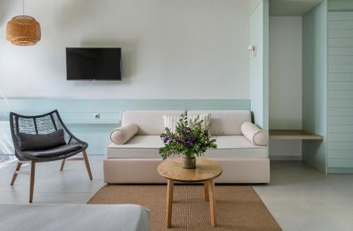 a living room with a couch and a table with flowers at Callisto Seaside Homes & Suites in Marathopolis
