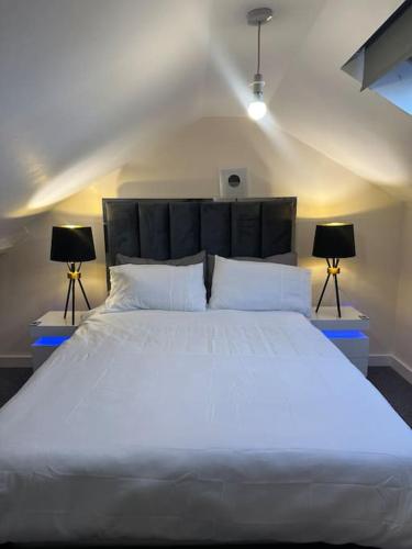 ダービーにあるModern 1 Bed Flat In Derby Cityのベッドルーム(白い大型ベッド、ランプ2つ付)