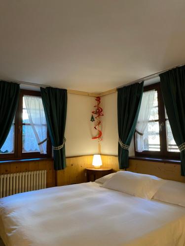 una camera da letto con un grande letto bianco e finestre di Baita Reale ad Alagna Valsesia