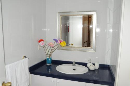 baño con lavabo con espejo y flores en Villa Bahia Meloneras, en Meloneras
