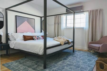 a bedroom with a four post canopy bed with a chair at Designer 1BR 1BA Culver City Sony Studios in Los Angeles