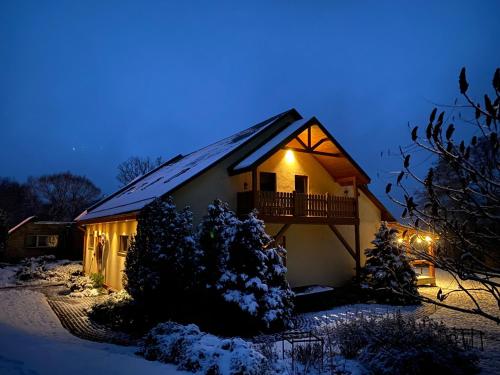 a house with a balcony in the snow at night at Dzintara Pirts in Vigale