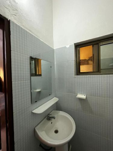 a white bathroom with a sink and a mirror at Private Room In Cotonou Home in Cotonou