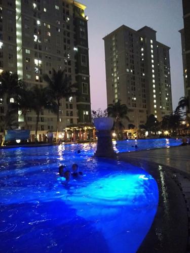 a pool with blue lights in a city at night at Riz Property in Jakarta