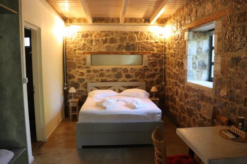 een slaapkamer met een bed in een bakstenen muur bij FARMAHOUSE in Orchomenós
