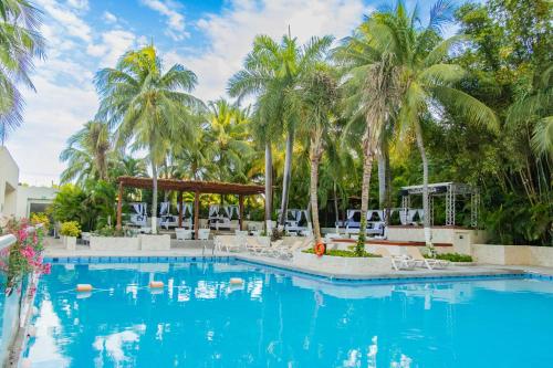 una piscina en un complejo con palmeras en Oh! Cancun - The Urban Oasis & beach Club en Cancún