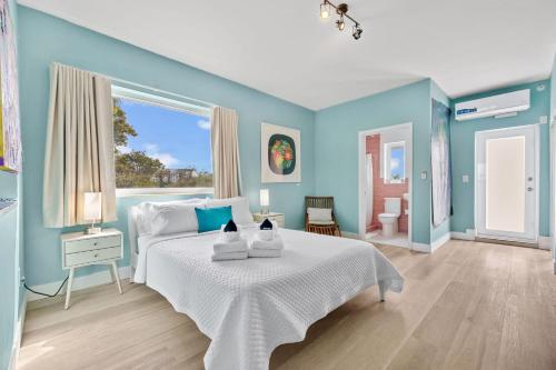 ein blaues Schlafzimmer mit einem weißen Bett und einem Fenster in der Unterkunft The New Yorker Miami Hotel in Miami