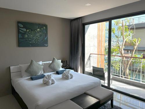 um quarto com uma cama branca e uma grande janela em Private apartment at Emerald Terrace em Praia de Patong