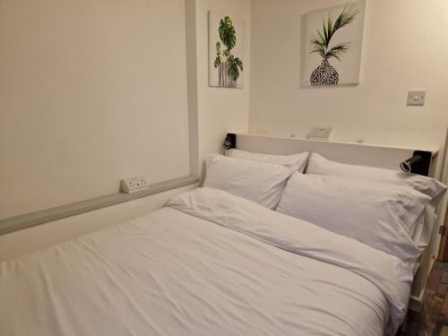 a white bed with white sheets and pillows at The Little Annex in Horsham