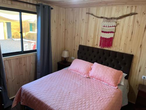 a bedroom with a bed with pink sheets and a window at Cabañas Doña Regina in Constitución