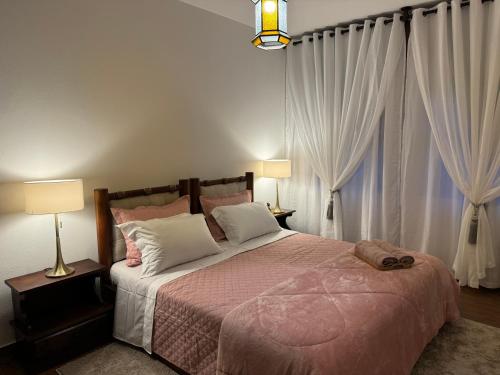 a bedroom with a large bed with white curtains at Casa Holanda in Teresópolis