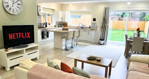 a living room with a couch and a tv and a kitchen at Modern and Spacious 3 Bed House, Sleeps 5, Close to Southampton City Centre, in Southampton