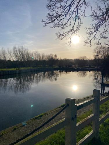 a fence next to a lake with the sun in the sky at Pershore Rooms at The Star in Pershore