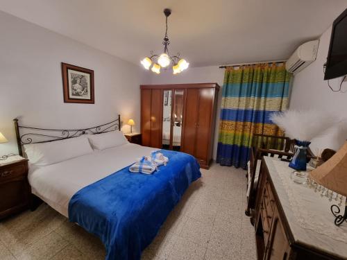 a bedroom with a large bed with a blue blanket at LA FUENTE ROMANA in Campo-Nubes
