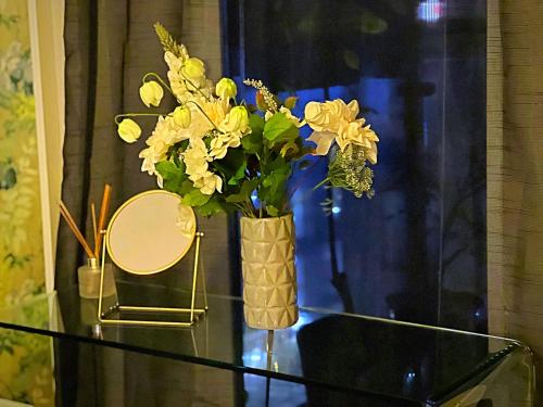 a vase with yellow flowers on a glass table at Latitude Chinatown Central Apartment in Birmingham