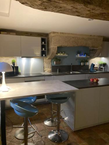 una cocina con una isla grande con 2 taburetes de barra azul en maison cocooning, en Gesnes-le-Gandelin