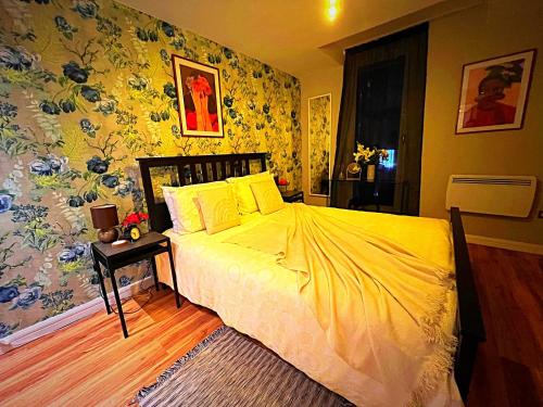 バーミンガムにあるLatitude Chinatown Central Apartmentのベッドルーム1室(黄色いシーツと花の壁紙を使用したベッド1台付)