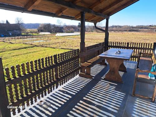 a wooden table and chairs under a pavilion with a field at Apartman T&N 