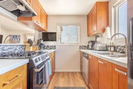 a kitchen with wooden cabinets and a stove top oven at Spectacular Ocean and Pier View Lux Family Vacation in Manhattan Beach