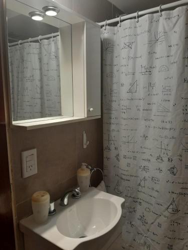 a bathroom with a sink and a shower curtain with writing at Excelente departamento en Villa Luro in Buenos Aires