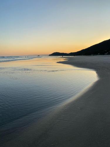 a beach with the sun setting on the water at Pousada Yamandu - Piscinas Aquecidas in Juquei