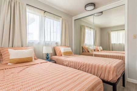 a bedroom with two beds and a large mirror at Downtown Manhattan Beach 3 Bed Townhouse Parking in Manhattan Beach
